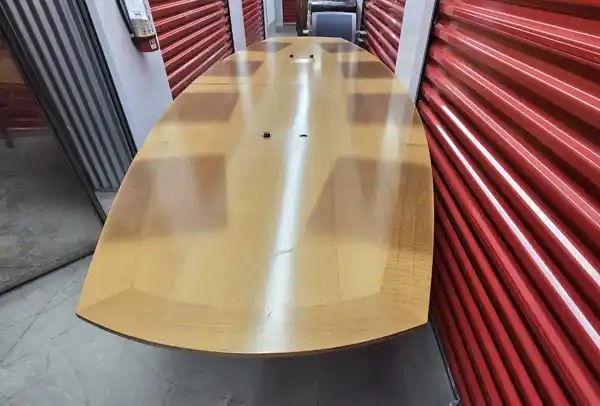 Angled view of long conference table with speaker ports, placed in red storage corridor