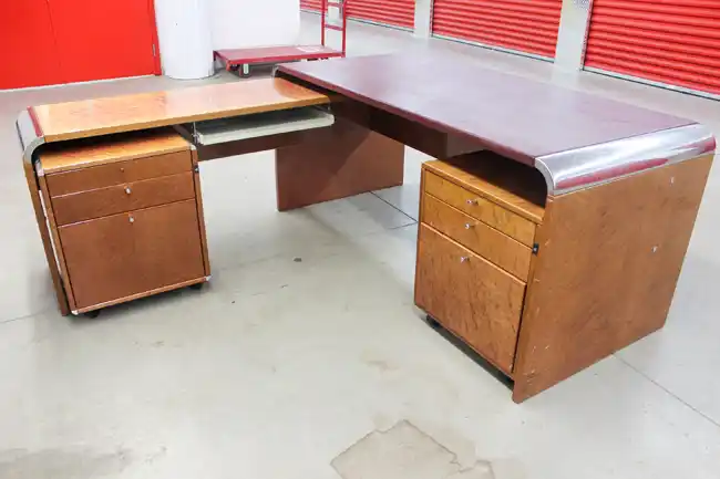 Full view of L-shaped birdseye maple desk with chrome corners, keyboard tray, and pedestals
