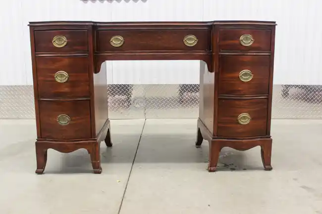 Front view of traditional mahogany kneehole desk with brass pulls