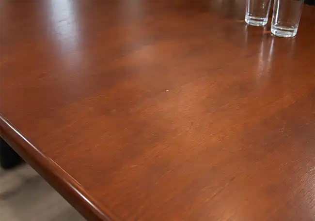 Close-up view of the mahogany-colour boardroom table surface showing light wear consistent with pre-owned condition.